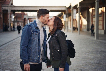 Young pregnant couple kissing on the street. Celebration of pregnancy. Lifestyle couple. 