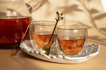 Double-bottom glasses are stacked on top of each other. Natural motives in warm colors. Breakfast glasses with tea. A spoon in the shape of a leaf. 
