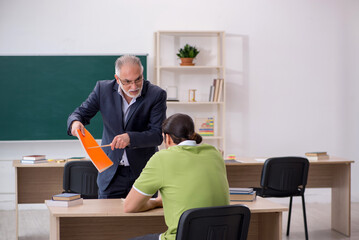 Aged teacher and young male student in the classroom