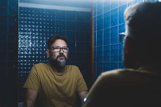 portrait of sad and depressed man looking at himself in the mirror