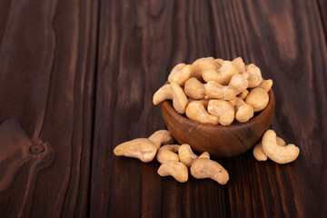Cashew nutsin wooden bowl, on wooden background. Roasted cashew nuts.