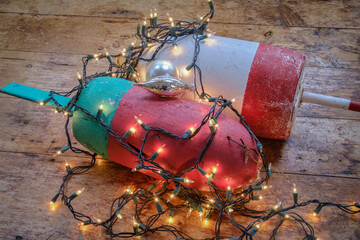 Colorful Maine Red green and white lobster float buoys surrounded by Christmas holiday lights