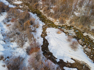 Winter landscape in the mountains during the thaw, a photograph of a mountain river from a drone