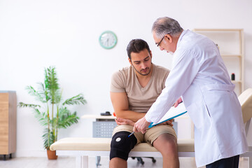 Experienced doctor traumatologist examining young male patient