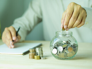 Men's hand put coin in glass jar.Money management planing and financial concept.