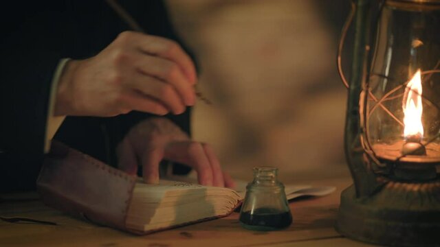 Nineteenth century scene lit by the warm glowing light from an oil lantern of a man writing in a journal using a dip pen.