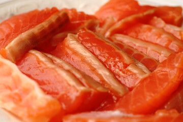 The pieces of red fish on the plate are evenly sliced.