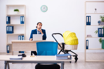 Young male employee looking after kid at workplace