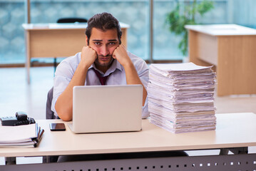 Young male employee unhappy with excessive work in the office