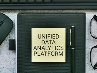 Phrase UNIFIED DATA ANALYTICS PLATFORM written on sticky note with pen,book,wireless mouse,keyboard...