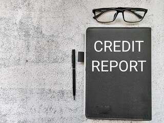 Phrase CREDIT REPORT written on note book with pen and eye glasses. Business concept.