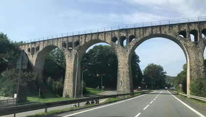 Old arched stone bridge over a road in Germany
