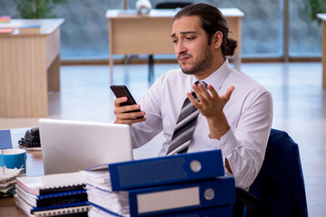 Young male employee unhappy with excessive work in the office