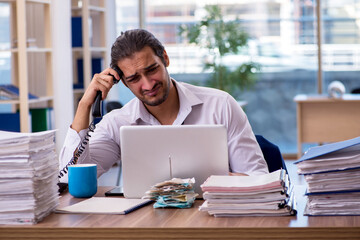 Young male employee unhappy with excessive work in the office