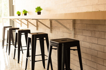 Cream wall bar interior with a wooden bar and stools near it.