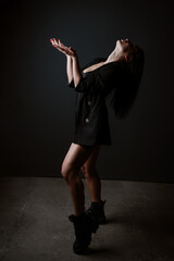 Portrait of a beautiful woman in a black bodysuit and jacket on a dark background