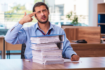 Young male employee unhappy with excessive work in the office