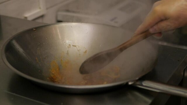 a chef prepares fried pieces of meat, peppers in a huge wok in a restaurant - a close-up view. cooking pasta in a large wok