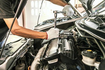 Fototapeta na wymiar Close-up hands of auto mechanic are using the wrench to repair and maintenance auto engine is problems at car repair shop. Concepts of car care check and fixed and services insurance.