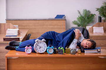 Young male employee sleeping in the office in time management co