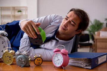Young male employee sleeping in the office in time management co