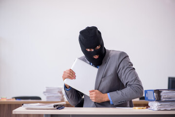 Young male employee in industrial espionage concept