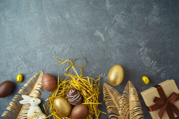Easter holiday concept with golden Easter eggs and gift box on dark background