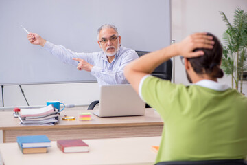 Old male teacher and young male student in the classroom