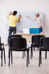 Young male student and experienced teacher in pandemic concept