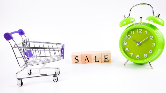 An imagr of trolley, green clock and wooden block aplhabet "SALE" isolated on a white background. Shopping concept.