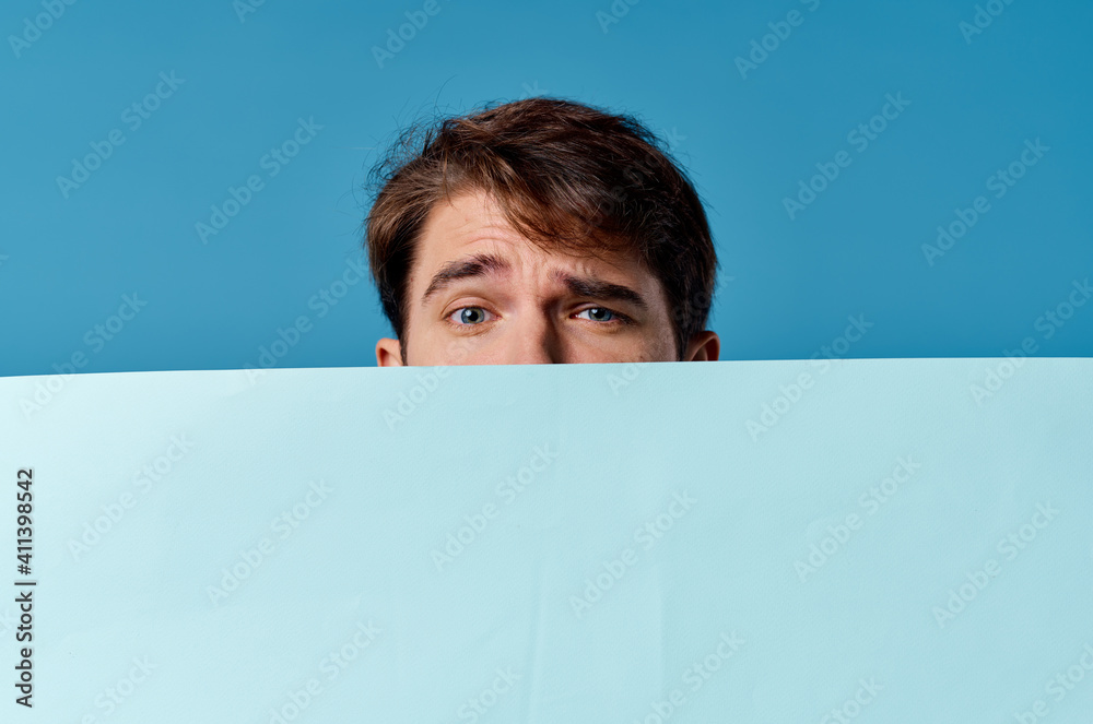 Wall mural a man peeking out from behind a banner close-up advertising copy space marketing