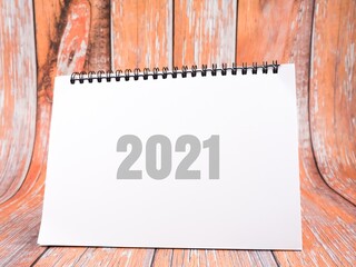 An image of notebook written "2021" isolated on a wooden background. New year concept.
