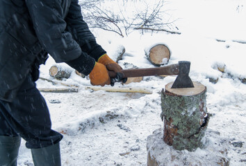 a man splits a tree stump in winter