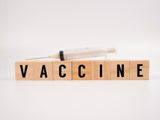 An image of syringe on the wooden blocks alphabet "VACCINE" isolate on a white background. Medical concept.