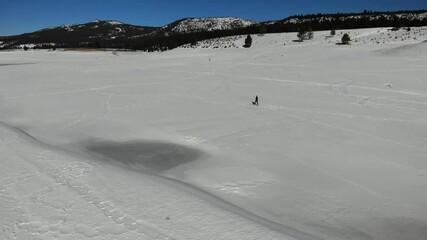  Drone ascension over cross country skier in black clothing on a flat plane in the winter