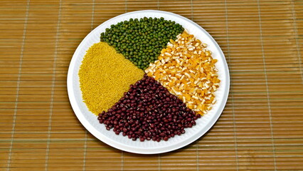 Top view of various grains in a round plate with mung beans, corn, millet
