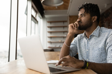 Pensive young afro guy student take distant test exam from home think before type choose correct...