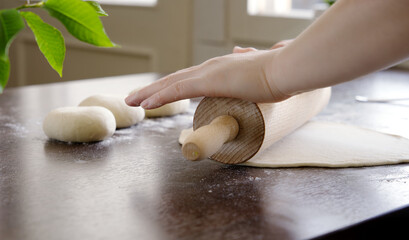 Closeup of rolling the dough into pancakes with a rolling pin