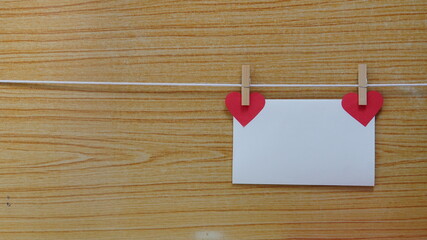 two red hearts hanging on a line on wooden table. Copy space