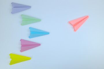 Pink paper airplane flying in multicolor paper airplanes.