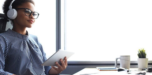 Beautiful african american woman is working using digital tablet while sitting in creative office.