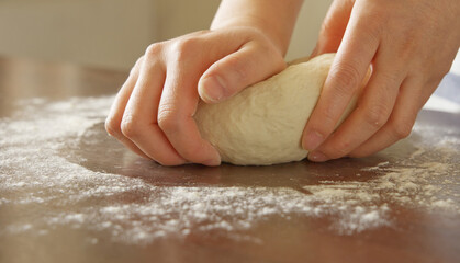 Closeup of woman's hands kneading dough, homemade flour-made food concept