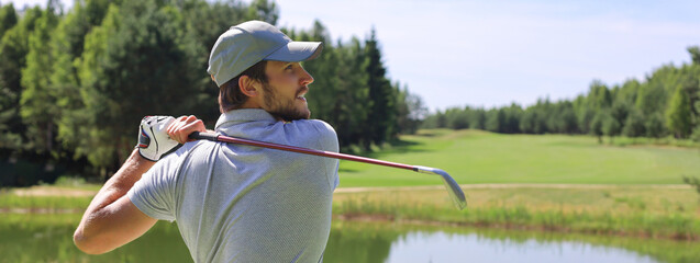 Golfer hits an fairway shot towards the club house.