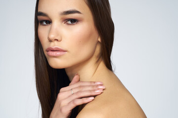 Fototapeta premium Pretty brunette naked shoulders long hair close-up light background
