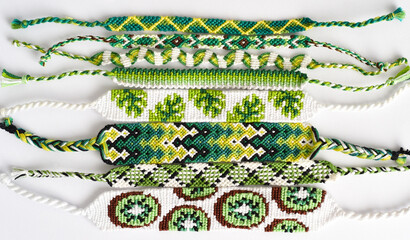 Woven DIY friendship bracelets handmade of embroidery floss with knots in green colors