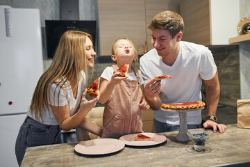 Dad, mom and daughter are having breakfast in the kitchen, cutting a pie with berries. baked goods ourselves