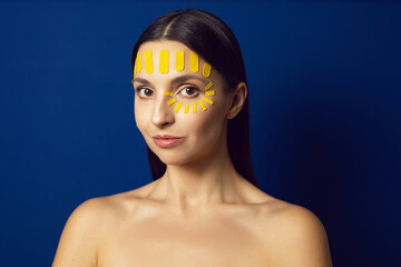 portrait of a girl on a yellow background with a kinesiotape of the face on the forehead