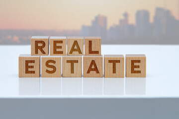 'Real Estate' message sign on wooden blocks sitting on a white table.