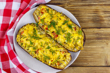 Baked stuffed eggplants on a wooden table. Top view. Healthy food and dieting concept