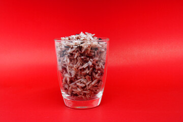 Brown rice in glass on red bacckground